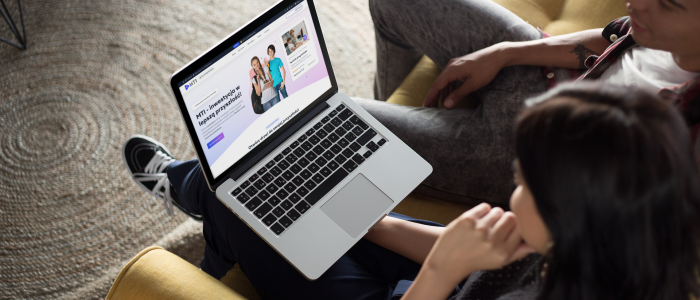 Dwoje młodych ludzi (chłopak i dziewczyna) siedzących na kanapie i oglądających stronę WWW na laptopie.